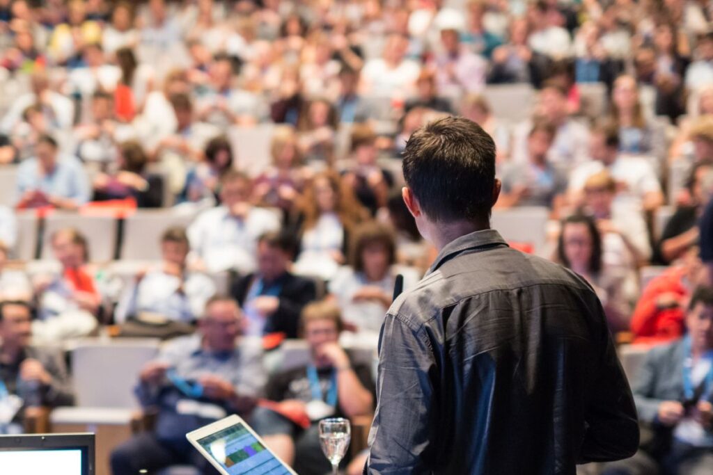 young man speaking in front of crowd